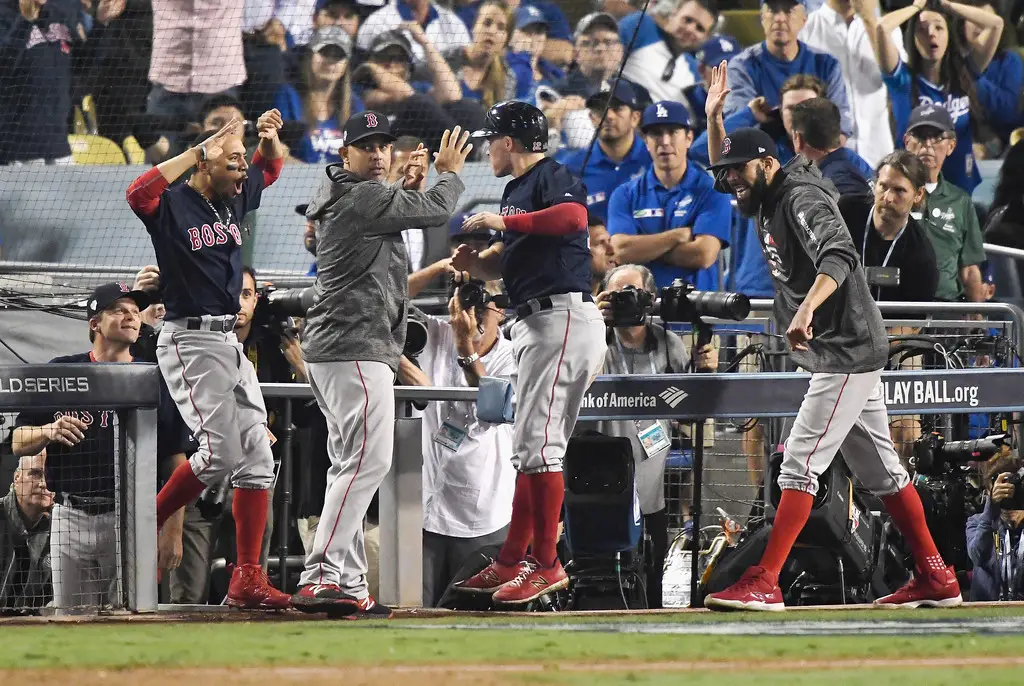 Boston Red Sox manager Alex Cora celebrating with Brock Holt after he scores a run in Game 3 of the World Series
