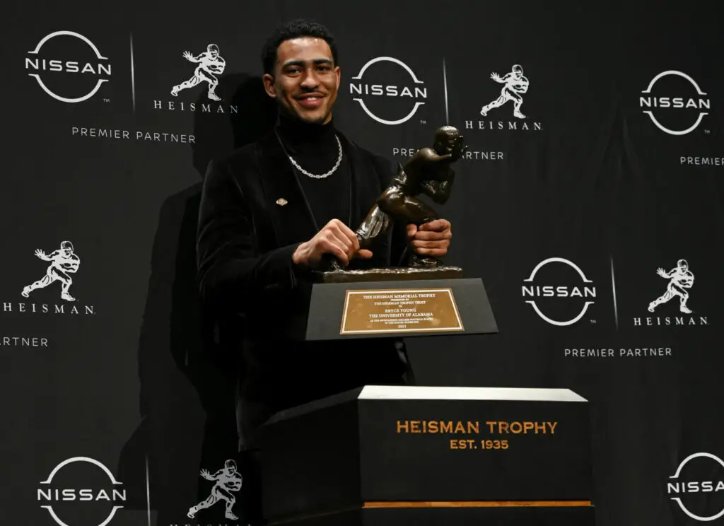 Alabama Crimson Tide quarterback Bryce Young raises the Heisman Trophy After winning the prestigious award