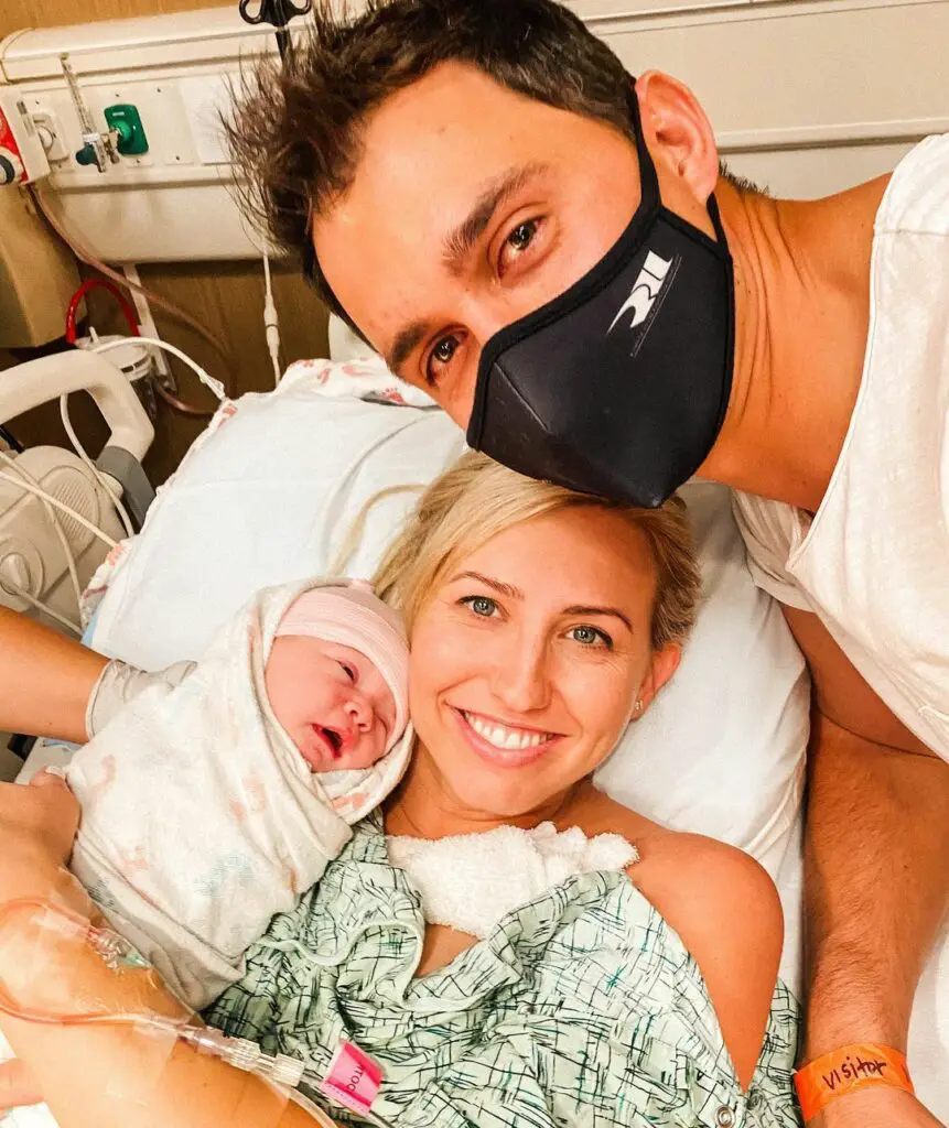 Former NHRA Funny Car driver Courtney Force holding her new daughter Harlan Rahal with her IndyCar driver Graham Rahal looking over the two women