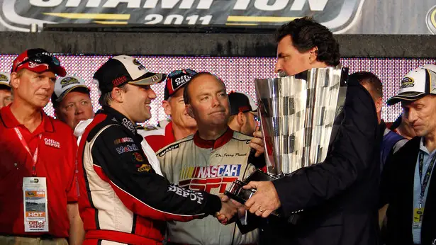 NASCAR Cup Series Champion Tony Stewart shakes hands with NASCAR President Mike Helton in Victory Lane after winning the NASCAR Cup Series Ford 400 and the 2011 Series Championship
