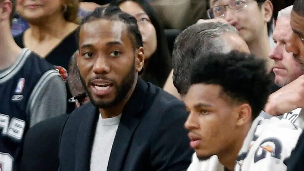 San Antonio Spurs star Kawhi Leonard sits on the bench in street clothes during a game against the New Orleans Pelicans