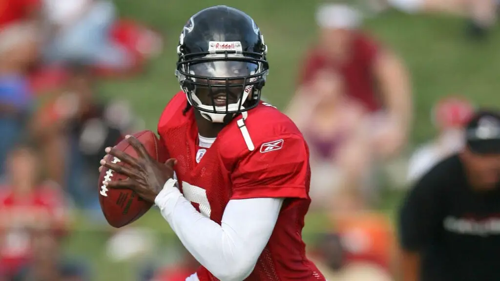 Former Atlanta Falcons quarterback Michael Vick rolls out to throw a pass during training camp at the Atlanta Falcons Training Complex