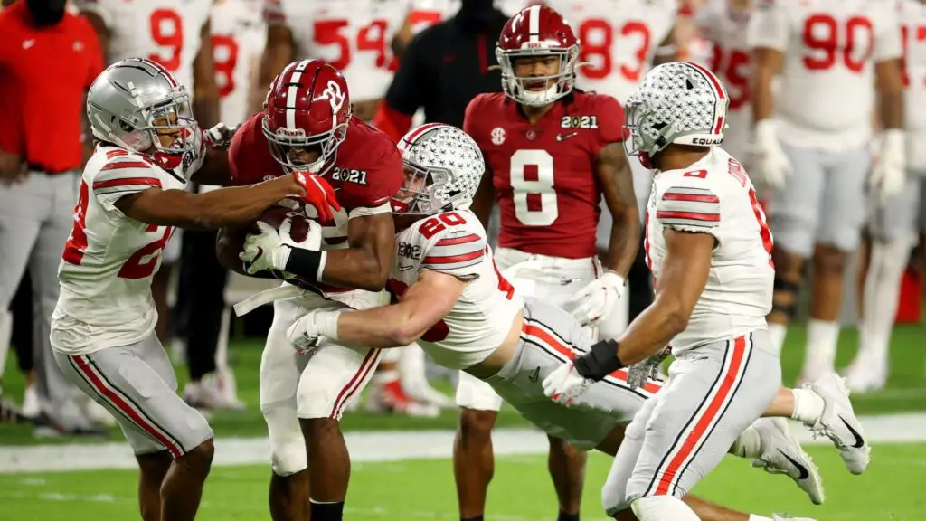 Alabama Crimson Tide running back Najee Harries carries the football as Ohio State Buckeyes players Peter Werner and Shaun Wade attempt to tackle him during the College Football Playoff National Championship Game