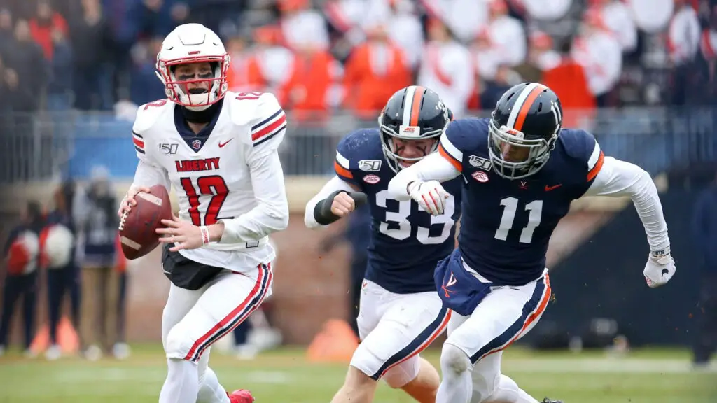 Liberty Flames quarterback Stephen Calvert attempts to throw a pass as Zane Zandier and Charles Snowden chase him down against the Virginia Cavaliers in the first half during a game