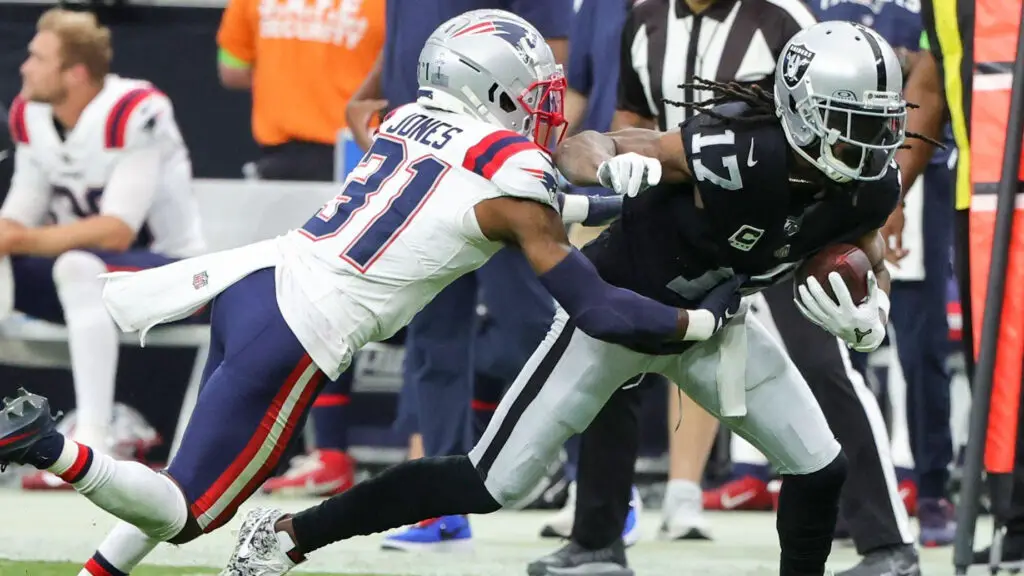 Las Vegas Raiders wide receiver Davante Adams is being tackled by New England Patriots cornerback Jonathan Jones after a catch in the second quarter of their game