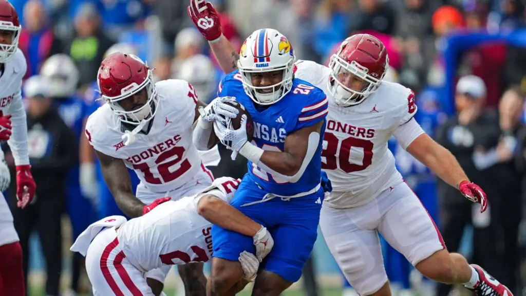 Kansas Jayhawks running back Daniel Hishaw Jr. is tackled by Oklahoma Sooners players Billy Bowman, Key Lawrence, and Rondell Bothroyd during the first half