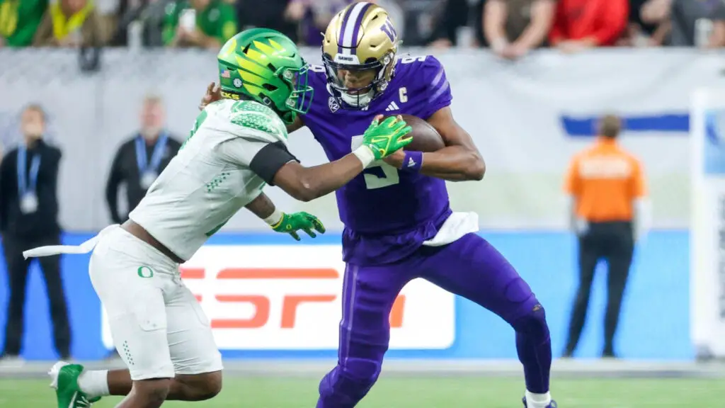 Washington Huskies quarterback Michael Penix Jr. tries to avoid a tackle from Oregon Ducks defensive player Jamal Hill during the fourth quarter during the Pac-12 Championship