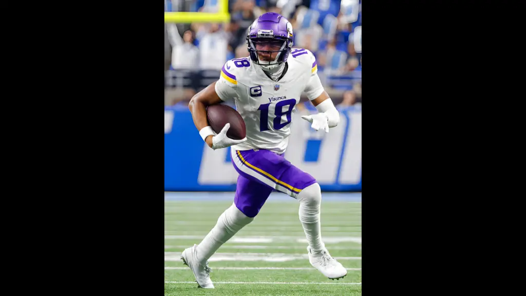 Minnesota Vikings star wide receiver Justin Jefferson runs with the football up the field after a catch during the first half of a game against the Detroit Lions