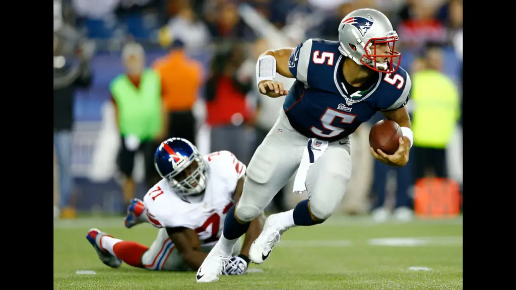 Former New England Patriots quarterback Tim Tebow evades a tackle and runs with the ball past Adewale Ojomo against the New York Giants during the preseason game