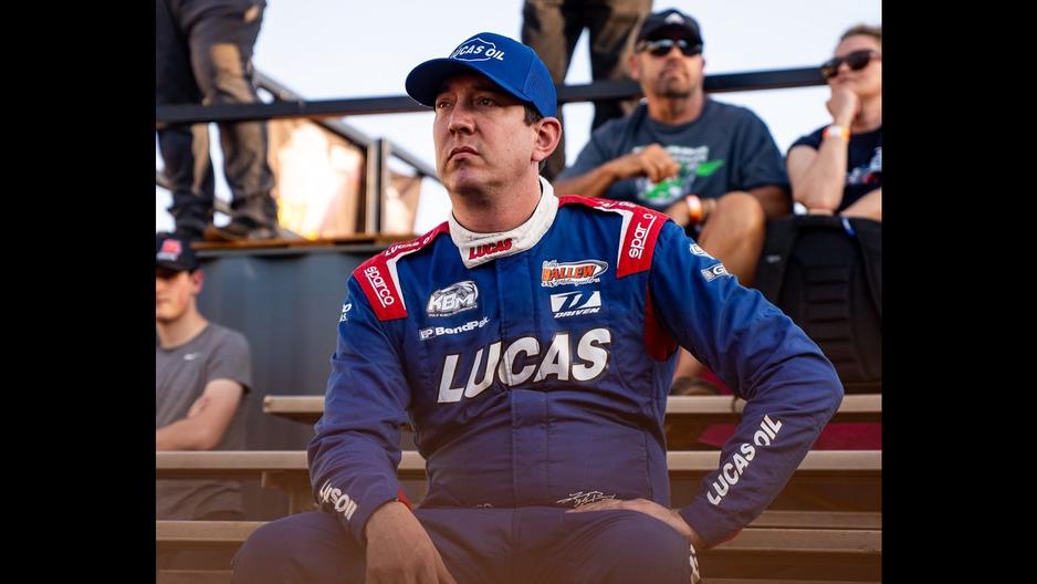 Kyle Busch sitting in the stands of a dirt track race