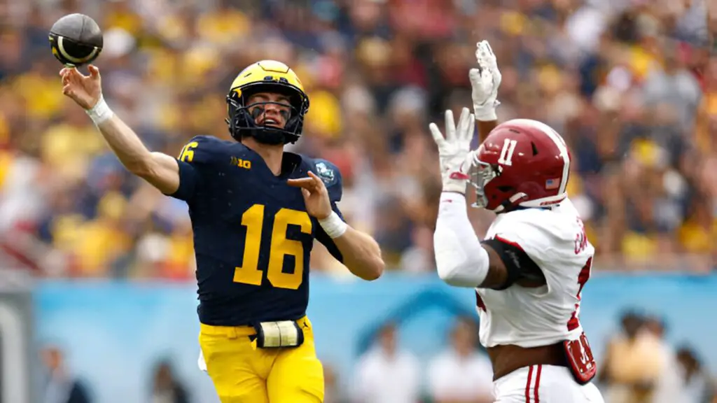 Michigan Wolverines quarterback Davis Warren throws a pass while pressured by Jihaad Campbell against the Alabama Crimson Tide during the first quarter in the 2024 ReliaQuest Bowl