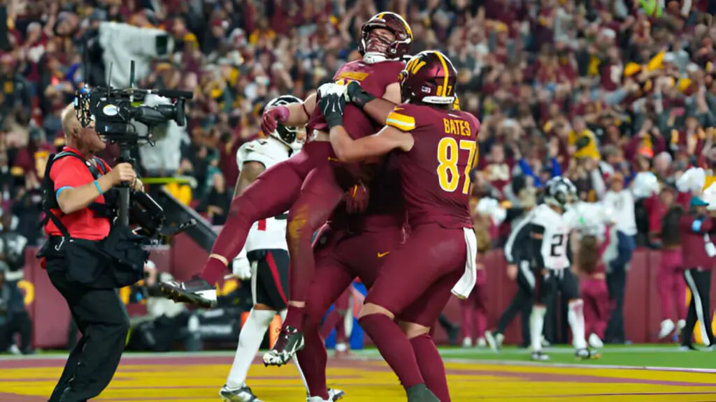 Washington Commanders Tight End Zach Ertz is hoisted by teammates after scoring a game-winning overtime touchdown during an NFL football game against the Atlanta Falcons